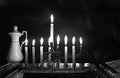 Burning Chanukah. The lit Chanukiah. Jewish holiday Hanukkah. Black and white photo. Porcelain jug with oil.