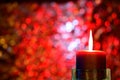 Burning Christmas candle against red bokeh background Royalty Free Stock Photo