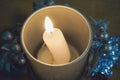 Burning Christmas candle in a candlestick decorated with festive Christmas decorations. Blue backlight, open candle flame Royalty Free Stock Photo