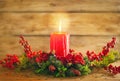 Burning Christmas red candle and festive Christmas arrangement on a wooden table