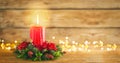 Burning Christmas red candle and festive Christmas arrangement on a wooden table