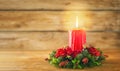 Burning Christmas red candle and festive Christmas arrangement on a wooden table