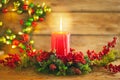 Burning Christmas red candle and festive Christmas arrangement on a wooden table