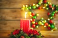 Burning Christmas red candle and festive Christmas arrangement on a wooden table