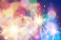 Burning christmas sparkler on colorful light background Royalty Free Stock Photo