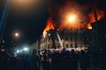 Burning city building at night, Firefighters extinguish house, Silhouettes of citizens people on foreground looks and