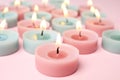 Burning colorful decorative candles on pink background