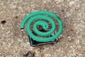 Burning dark green spiral mosquito repellent on metal stand left on concrete steps to repel mosquitoes and insects