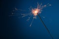 Burning festive Christmas sparkler on blue background Royalty Free Stock Photo