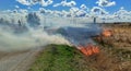 Burning field close to a road, dry grass on fire