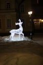 Burning figure of a deer in a quiet winter evening against the background of a historic building