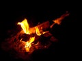 Burning firewood at night. Bonfire in a camping camp in nature in the mountains. Flames and fiery sparks on a dark Royalty Free Stock Photo