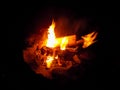 Burning firewood at night. Bonfire in a camping camp in nature in the mountains. Flames and fiery sparks on a dark Royalty Free Stock Photo