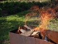 Burning firewoods in the rusty chargrill in a sunny summer day