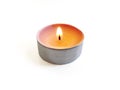 Isolated burning round candle. Front view of round tea light on white background. Burning flame in small round candle Royalty Free Stock Photo