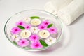 Burning floating candles with pink flowers in a bowl of water and two white towels, spa relaxation, body care and Royalty Free Stock Photo