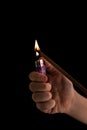 A burning gas lighter on a black background. A child's hand holds. Flame of fire. Royalty Free Stock Photo