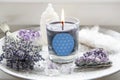 Burning glass candle with homemade sign showing Flower of Life symbol in home interior with semi precious stone geodes.