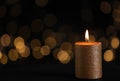 Burning gold candle against blurred lights in darkness Royalty Free Stock Photo