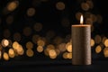 Burning gold candle against blurred lights in darkness Royalty Free Stock Photo