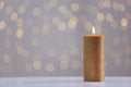 Burning gold candle on table against blurred lights. Royalty Free Stock Photo