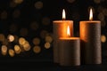 Burning gold candles against blurred lights in darkness Royalty Free Stock Photo
