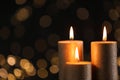 Burning gold candles against blurred lights in darkness. Royalty Free Stock Photo