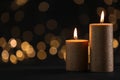 Burning gold candles against blurred lights in darkness. Royalty Free Stock Photo