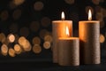 Burning gold candles against blurred lights in darkness Royalty Free Stock Photo