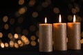 Burning gold candles against blurred lights in darkness. Royalty Free Stock Photo