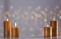 Burning gold candles on table against blurred lights Royalty Free Stock Photo