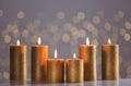 Burning gold candles on table against blurred lights. Royalty Free Stock Photo