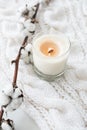Burning hand-made candle with cotton branch on white cozy winter