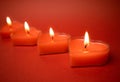 Burning heart-shaped candles with blazing flames, red background Valentine's Day Royalty Free Stock Photo