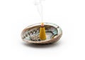 A burning incense cone is placed inside an abalone shell. The Royalty Free Stock Photo
