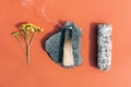 Burning incense - white sage and palo santo stick with smoke on stone stand over orange brown background Royalty Free Stock Photo