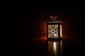 Burning lantern in the dark. Ornamental lantern with burning candle glowing at night. Wth a lot of empty space. Red orange fire ba Royalty Free Stock Photo
