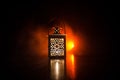 Burning lantern in the dark. Ornamental lantern with burning candle glowing at night. Wth a lot of empty space. Red orange fire ba Royalty Free Stock Photo