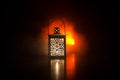 Burning lantern in the dark. Ornamental lantern with burning candle glowing at night. Wth a lot of empty space. Red orange fire ba Royalty Free Stock Photo