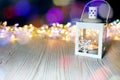 Burning lantern on white wooden background against blurry christ Royalty Free Stock Photo