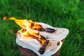 Burning leather sports shoes. Sneakers or gym shoes on fire stand on the Stump.