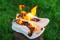 Burning leather sports shoes. Sneakers or gym shoes on fire stand on the Stump.