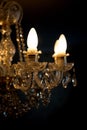 A burning light bulb on a crystal chandelier on a dark background Royalty Free Stock Photo