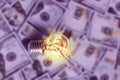 Burning light bulb on dollars background, expensive electricity Royalty Free Stock Photo