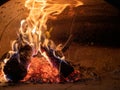 Burning logs, ashes, and intense flames in concrete oven