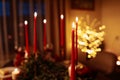 Burning long red candles on festive table for celebration Christmas and New Year holidays in living room on xmas tree Royalty Free Stock Photo