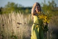 Burning with love, a young herbalist with a bouquet of herbs takes a sun bath at sunset. Common goldenrod and