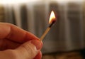 A burning match in the hand of a teenager. A match with a flame of fire on a dark background.