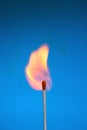 Burning match stick with fire and smoke on blue Royalty Free Stock Photo