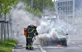 Burning motor vehicle been put out by firemen in protective clot Royalty Free Stock Photo